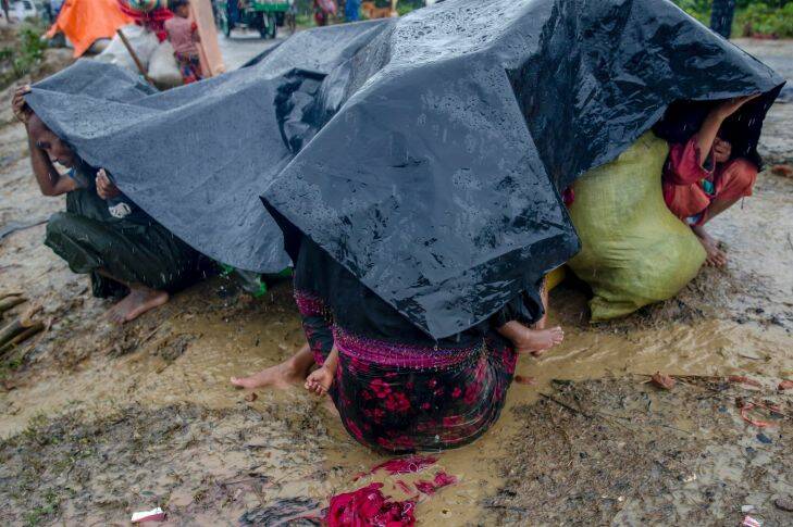 A Rohingya Muslim family, who crossed over from Myanmar into Bangladesh, take cover under a plastic sheet on a roadside during a rain storm near Balukhali refugee camp, Bangladesh, Sunday, Sept. 17, 2017. Bangladeshi authorities on Sunday took steps to restrict the movement of Muslim Rohingya refugees living in crowded border camps after fleeing violence in Myanmar. (AP Photo/Dar Yasin)