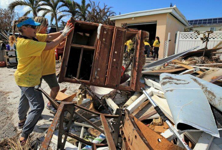 Maria Stotts, and Heather Mueller, volunteers from the Church of Jesus Christ of Latter-Day Saints, clear debris from a Monroe County sheriff's deputy's home damaged by a six-foot storm surge, Sunday, Sept. 17, 2017, in Big Pine Key, Fla. Residents were allowed to return to their homes in the Keys today a week after Hurricane Irma struck the Florida Keys (Al Diaz/Miami Herald via AP)