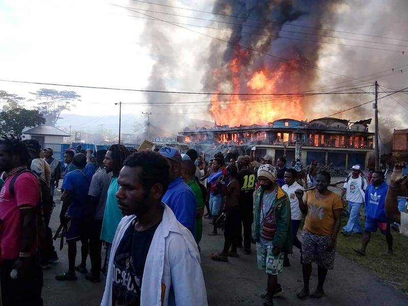 People gather as shops burn during a protest in Wamena in Papua province, Indonesia.